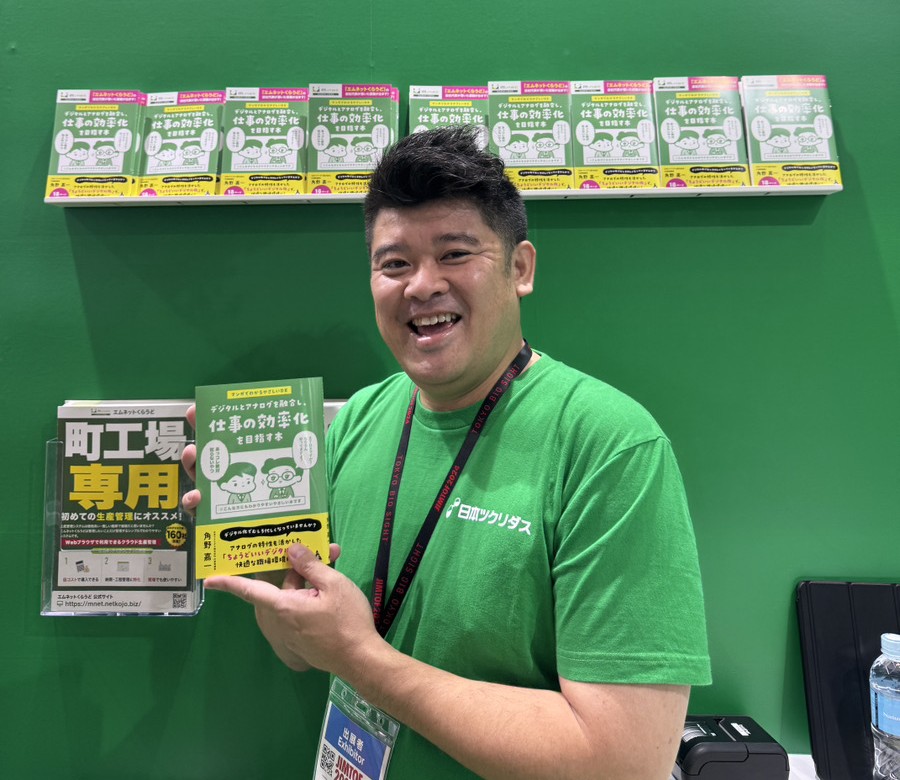 展示会ブースで著書を手に持つ角野嘉一代表