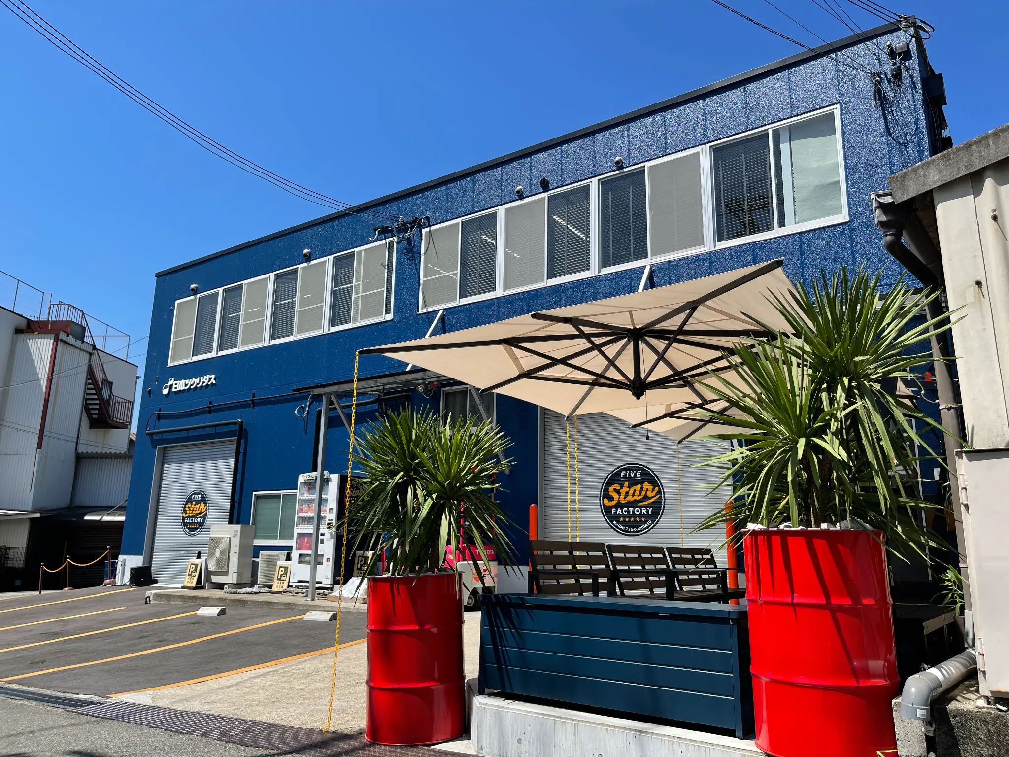 日本ツクリダス株式会社の社屋外観。青色の建物と、FIVE STAR FACTORYの看板が見える。