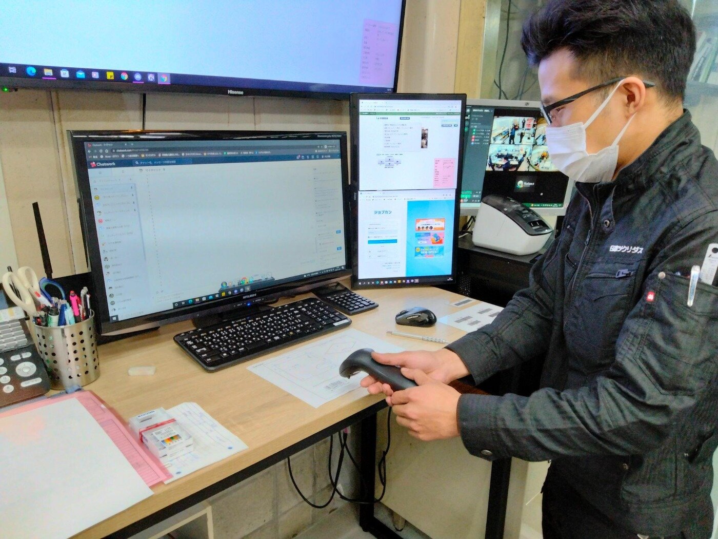 デスク上の図面に貼られたバーコードをハンディスキャナーで読み取る作業服姿の担当者