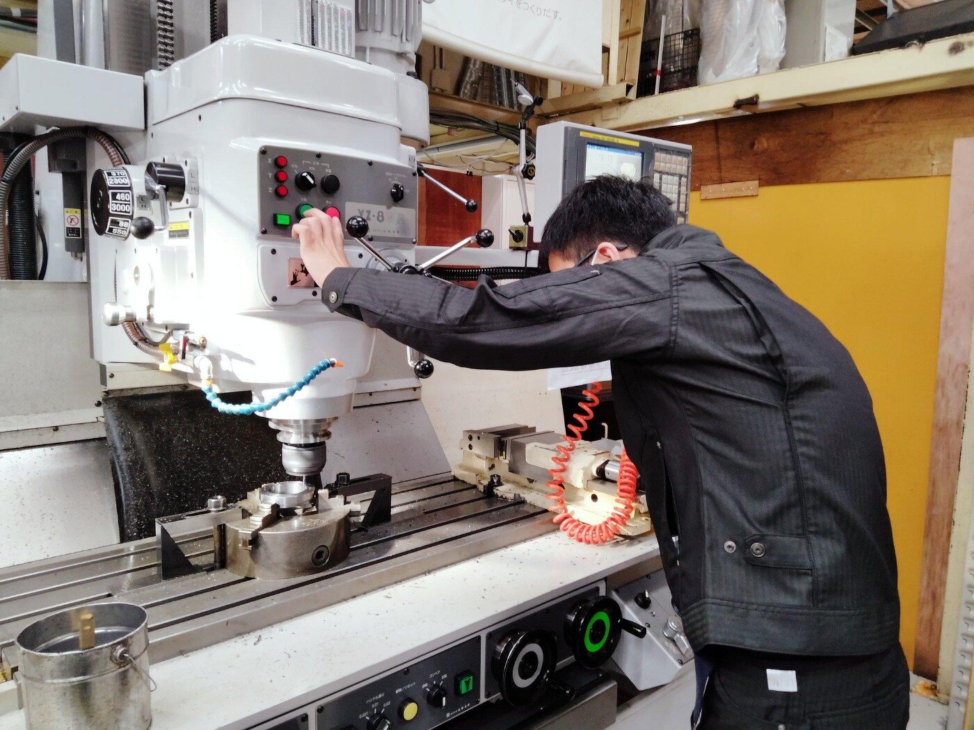 工作機械の操作パネルを操作し、金属加工の実際の作業を行う作業員