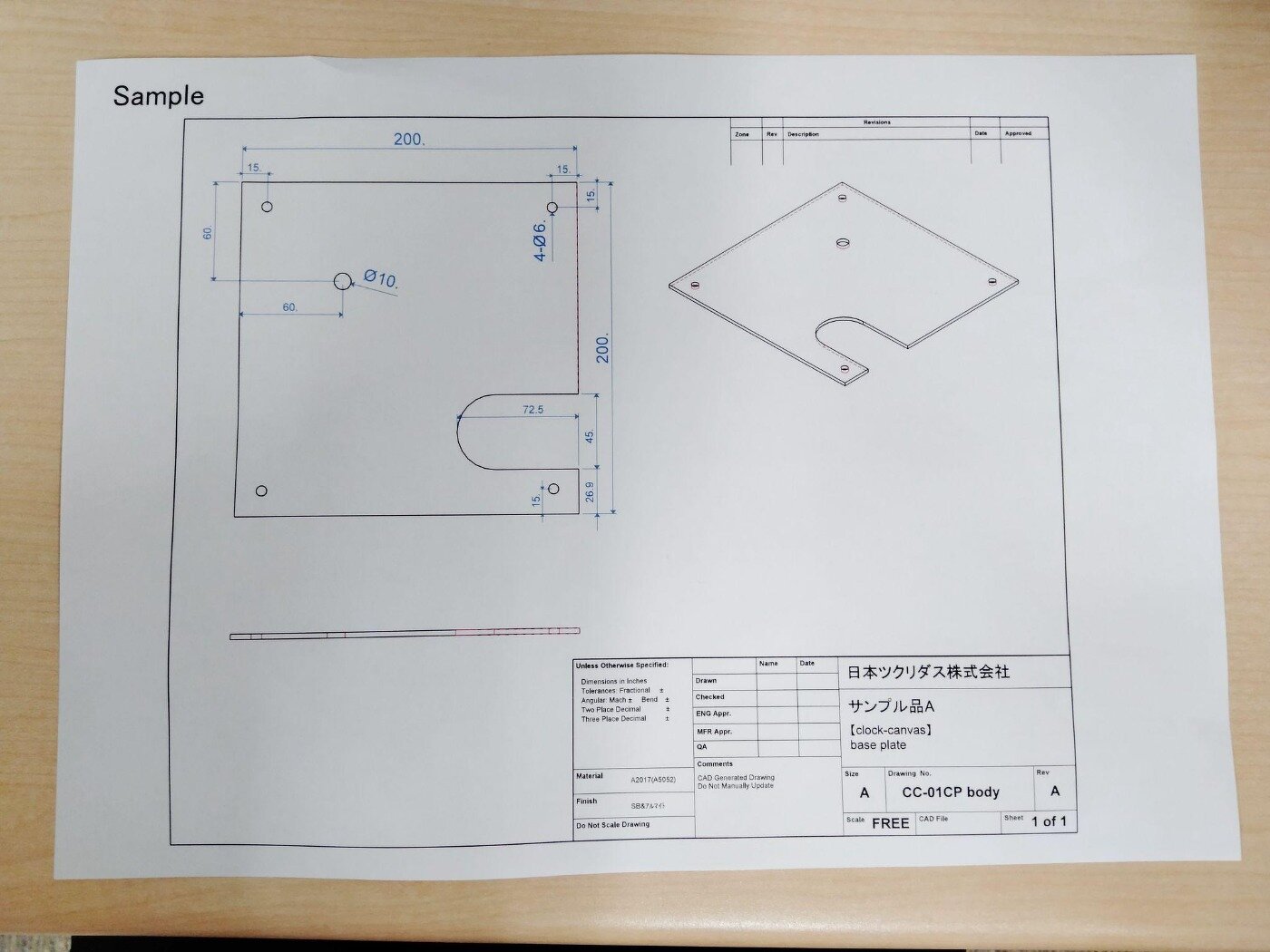 机の上に置かれた、寸法や部品名が記載された機械加工用の設計図面