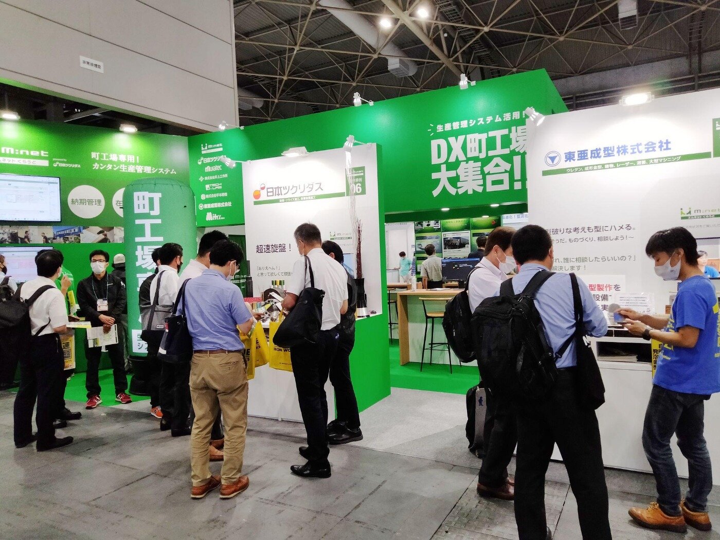 展示会「関西ものづくりワールド」の「DX町工場大集合！」共同出展ブースで、パネルや展示品を見学する来場者たち