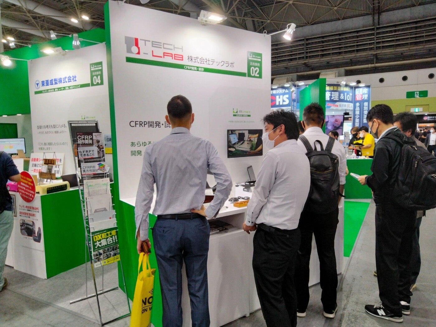 展示会の株式会社テックラボのブースで、モニター画面を見ながら説明を受ける来場者たち